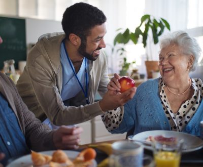 Smiling elderly woman and man enjoying breakfast in nursing home care center.
